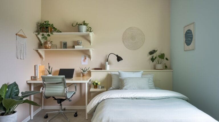 Cozy bedroom workspace featuring plants, desk with laptop, and minimalist decor, perfect for relaxation and productivity.