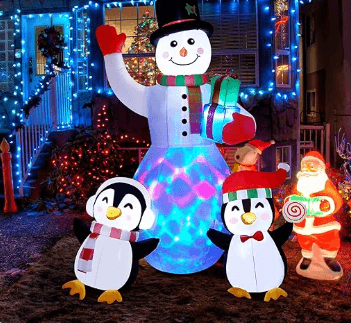 Colorful holiday decorations featuring a snowman and two penguins illuminated with festive lights in a cheerful winter scene.